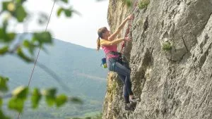 Young woman goes rock climbing up a mountain in Slovenian countryside.